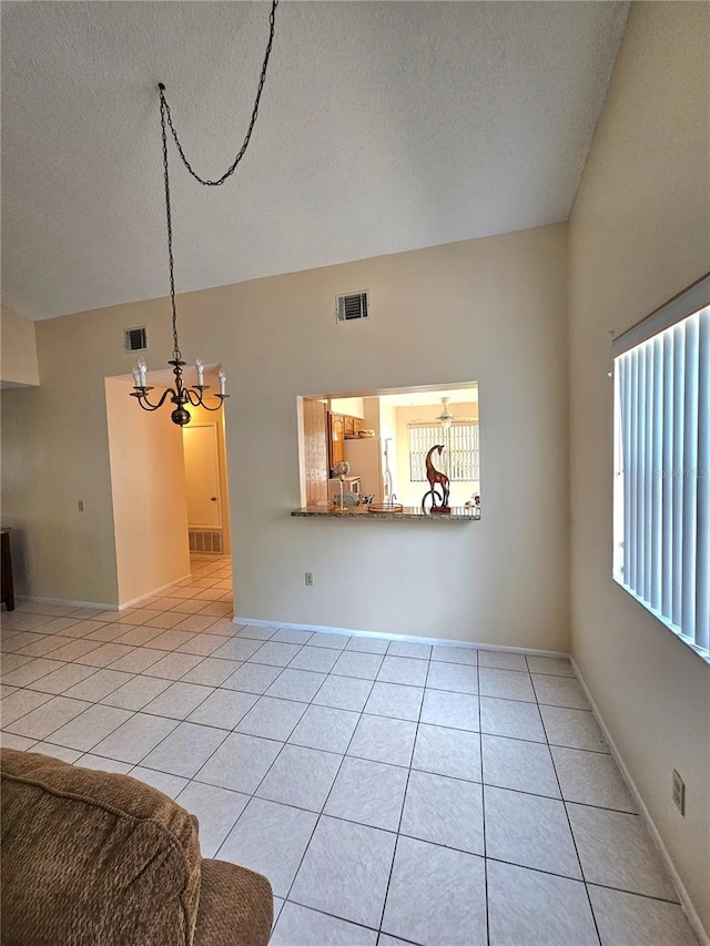 living room with light tile patterned floors, a textured ceiling, an inviting chandelier, and a healthy amount of sunlight