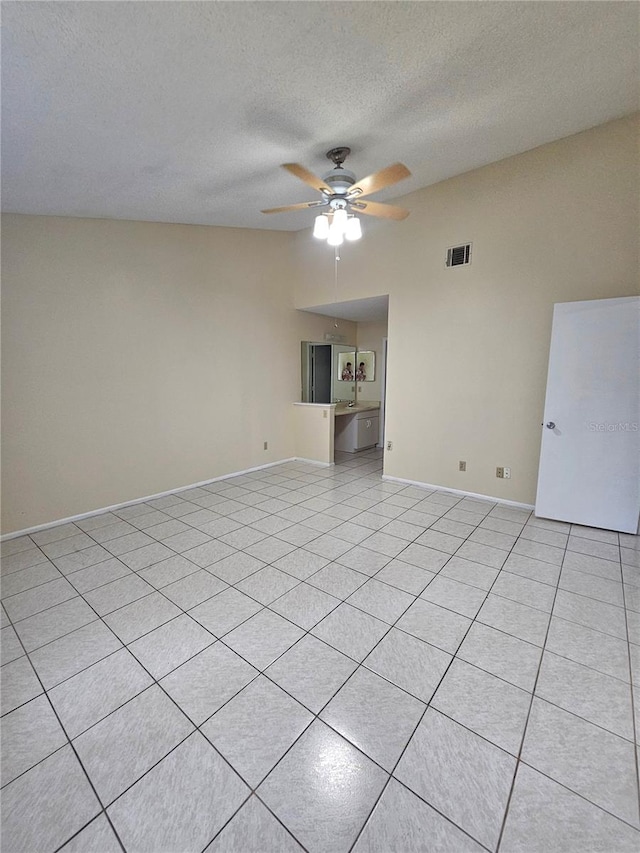 unfurnished living room featuring ceiling fan, light tile patterned floors, and a textured ceiling