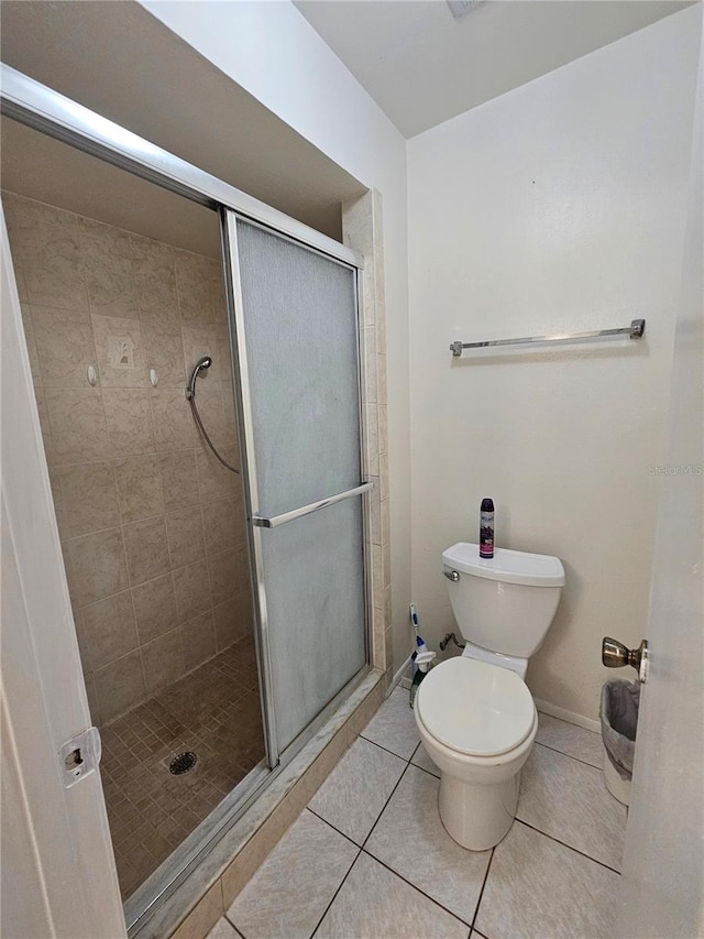 bathroom featuring tile patterned flooring, toilet, and walk in shower