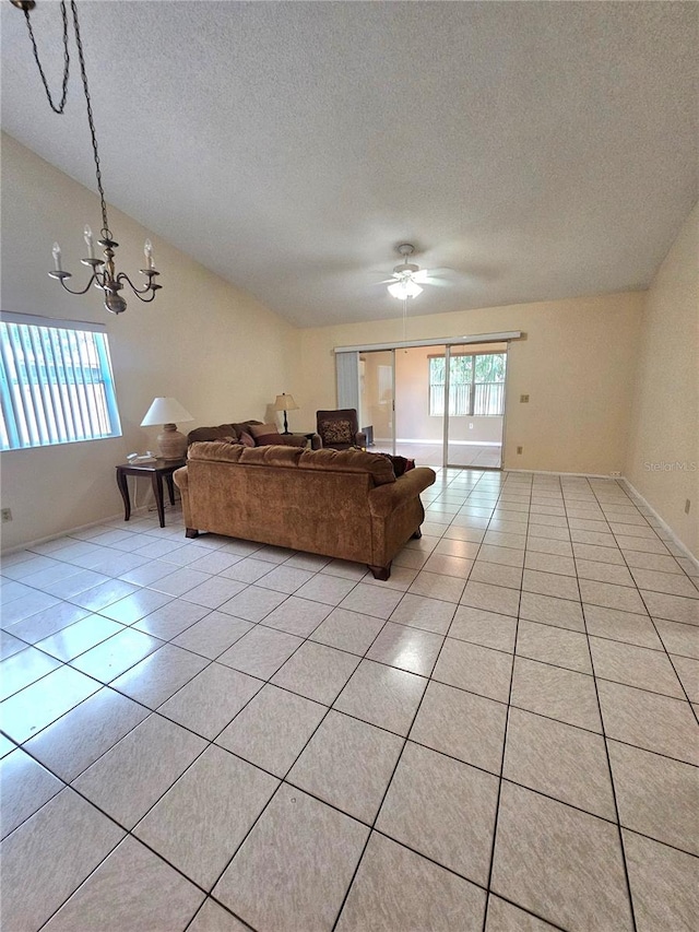 tiled living room with a textured ceiling and ceiling fan with notable chandelier