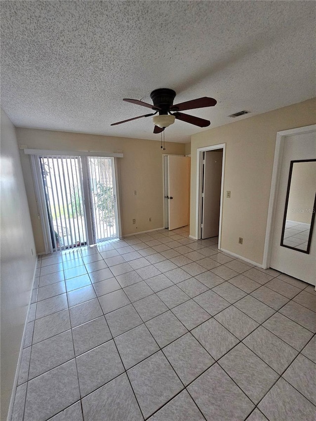 tiled empty room featuring ceiling fan and a textured ceiling