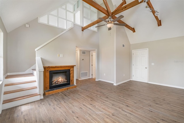 unfurnished living room with high vaulted ceiling, ceiling fan, track lighting, and hardwood / wood-style flooring