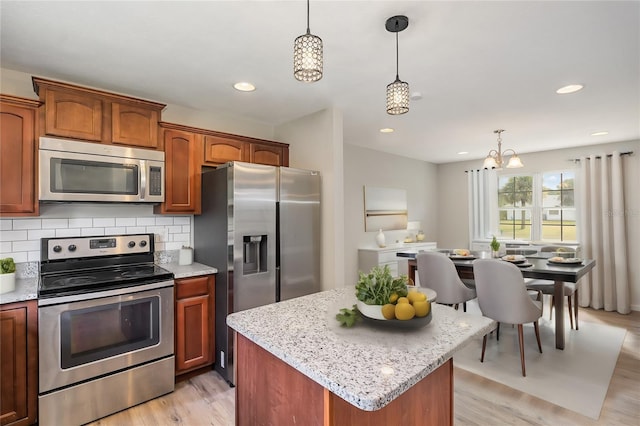 kitchen with tasteful backsplash, stainless steel appliances, light wood-type flooring, a kitchen island, and hanging light fixtures