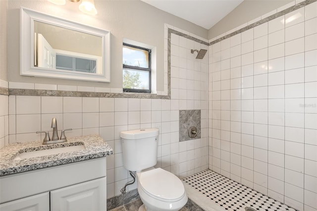 bathroom featuring tiled shower, tile floors, tile walls, vanity, and toilet