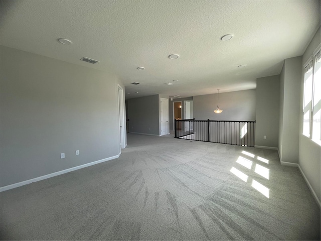 carpeted spare room with a textured ceiling