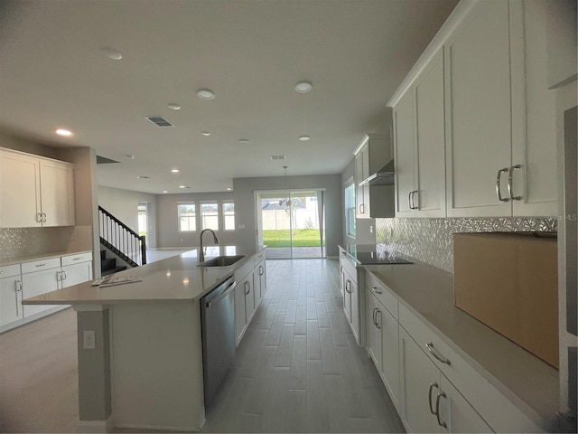 kitchen with stainless steel dishwasher, a kitchen island with sink, sink, and white cabinets