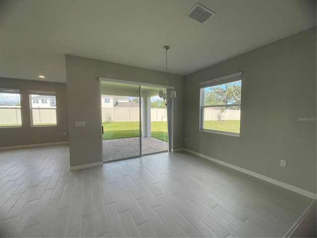 empty room featuring an inviting chandelier and light hardwood / wood-style floors