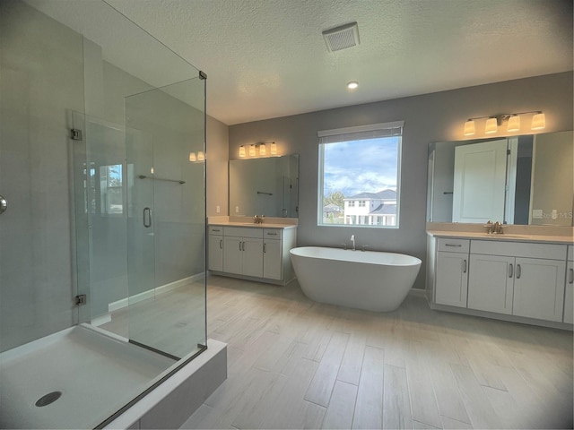 bathroom featuring vanity, hardwood / wood-style floors, independent shower and bath, and a textured ceiling