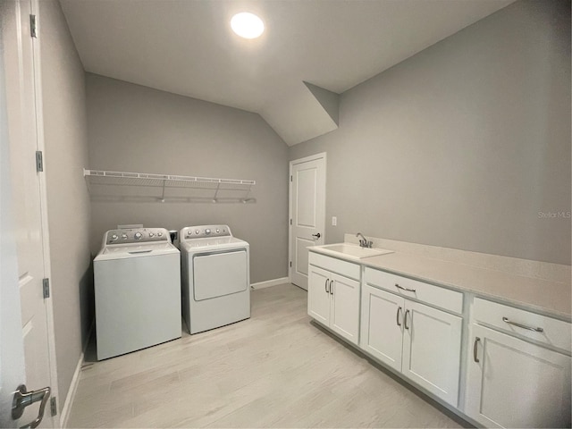 laundry area with cabinets, washing machine and clothes dryer, sink, and light hardwood / wood-style flooring