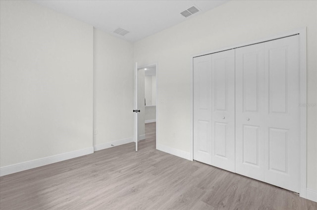 unfurnished bedroom with light hardwood / wood-style flooring and a closet