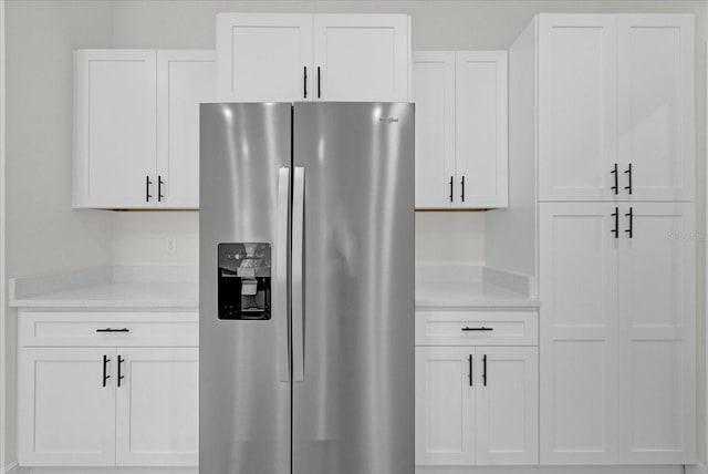 kitchen with stainless steel fridge and white cabinetry