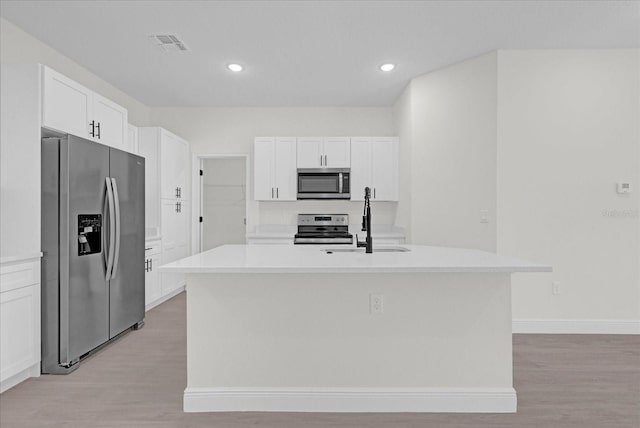 kitchen with white cabinets, appliances with stainless steel finishes, and a kitchen island with sink