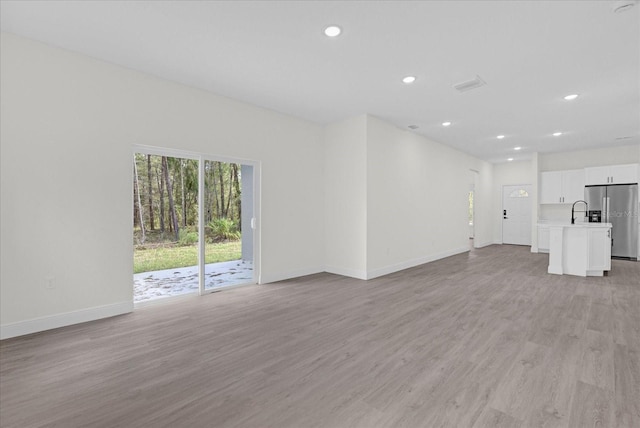 unfurnished living room with sink and light hardwood / wood-style flooring