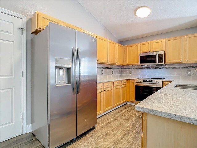 kitchen with light hardwood / wood-style flooring, lofted ceiling, tasteful backsplash, and stainless steel appliances