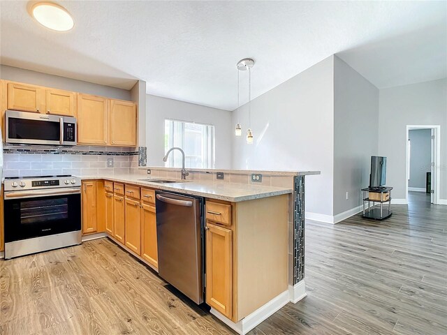 kitchen featuring sink, appliances with stainless steel finishes, kitchen peninsula, and light hardwood / wood-style flooring