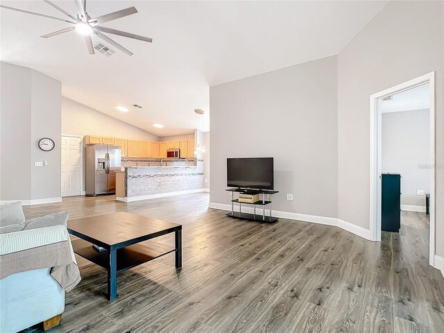 living room featuring wood-type flooring, ceiling fan, and vaulted ceiling