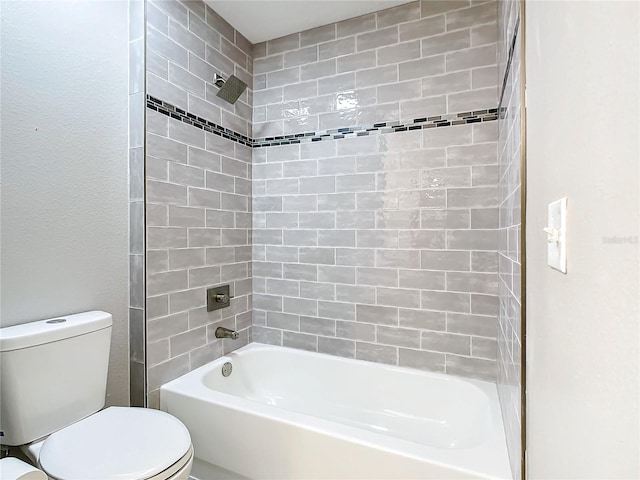 bathroom with tiled shower / bath combo and toilet