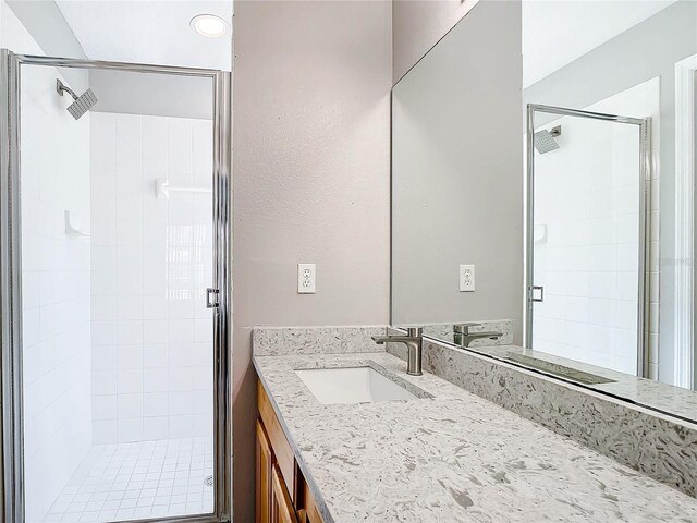 bathroom featuring a shower with door and vanity