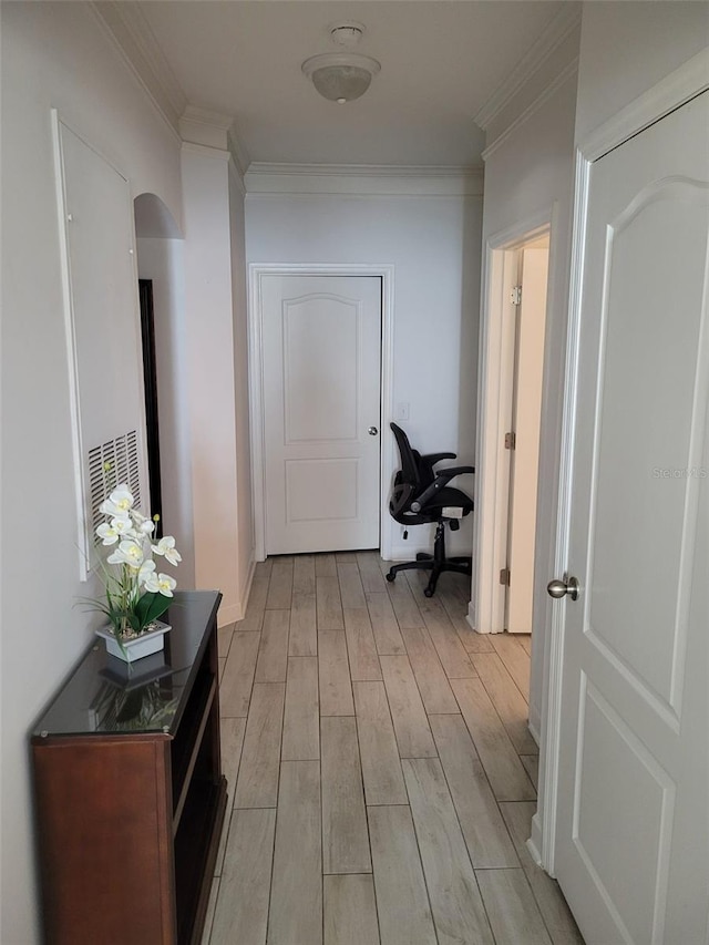 hallway with ornamental molding and light hardwood / wood-style flooring