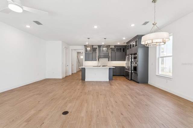 kitchen with light wood-type flooring, visible vents, backsplash, and light countertops