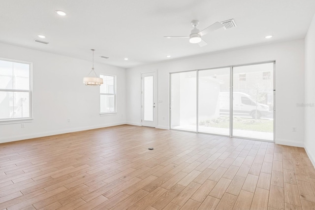 unfurnished living room with visible vents, baseboards, light wood-type flooring, recessed lighting, and ceiling fan with notable chandelier