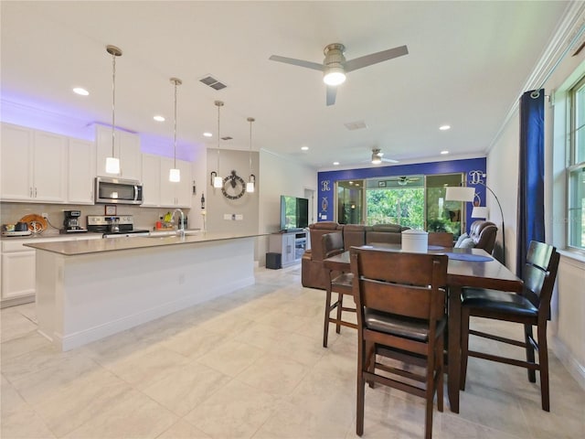 dining area featuring sink, ceiling fan, light tile floors, and crown molding