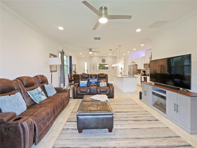 tiled living room featuring sink, ornamental molding, and ceiling fan