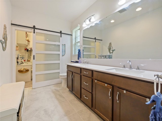 bathroom with vanity with extensive cabinet space, tile flooring, toilet, and dual sinks