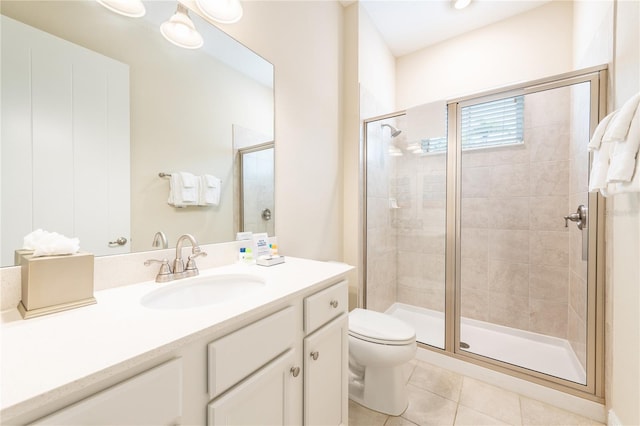 bathroom featuring toilet, vanity, tile patterned floors, and a shower with door