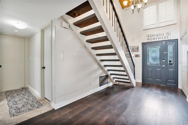 foyer with a high ceiling, hardwood / wood-style flooring, and an inviting chandelier