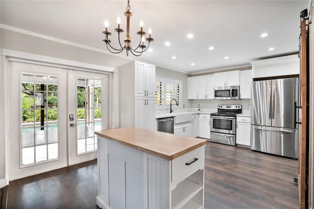 kitchen with white cabinetry, a wealth of natural light, dark hardwood / wood-style flooring, stainless steel appliances, and decorative light fixtures