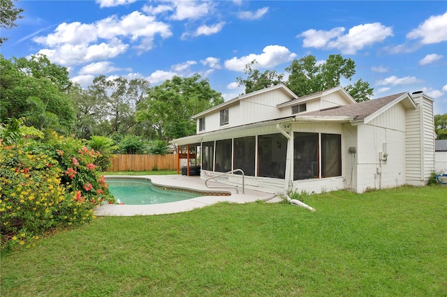 rear view of property featuring a patio, a sunroom, a yard, and a fenced in pool