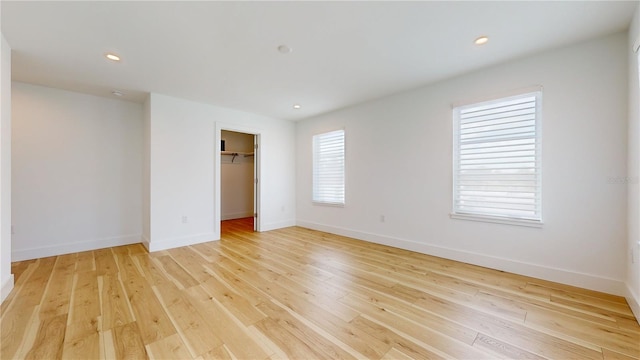 unfurnished bedroom with a closet, light wood-type flooring, and a spacious closet