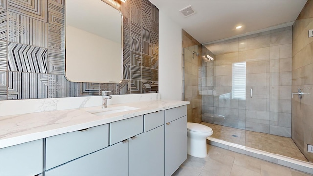 bathroom featuring toilet, vanity, tile patterned flooring, and a tile shower