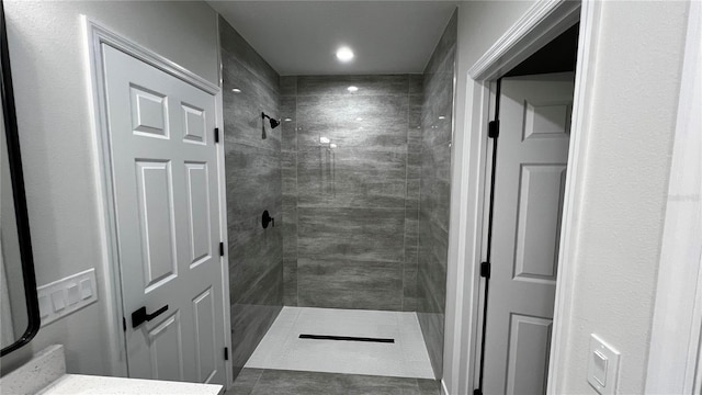 bathroom featuring tiled shower, vanity, and tile patterned flooring