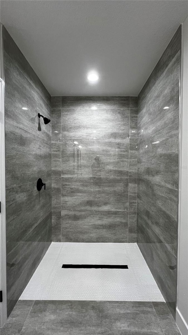 bathroom with tiled shower and tile patterned flooring