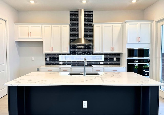 kitchen featuring white cabinets, a center island with sink, and oven