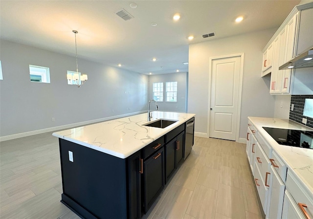 kitchen featuring hanging light fixtures, white cabinetry, sink, and an island with sink