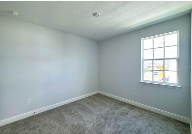 carpeted spare room featuring a textured ceiling