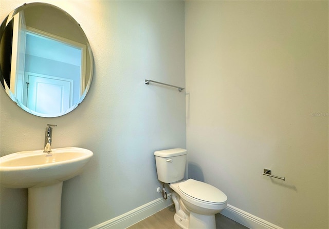 bathroom with wood-type flooring, toilet, and sink