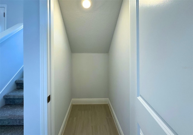 interior space featuring lofted ceiling, wood-type flooring, and a textured ceiling