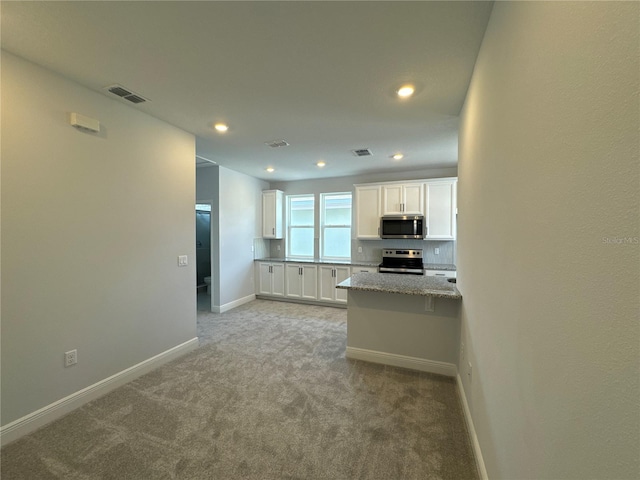 kitchen featuring white cabinetry, appliances with stainless steel finishes, light carpet, and light stone counters