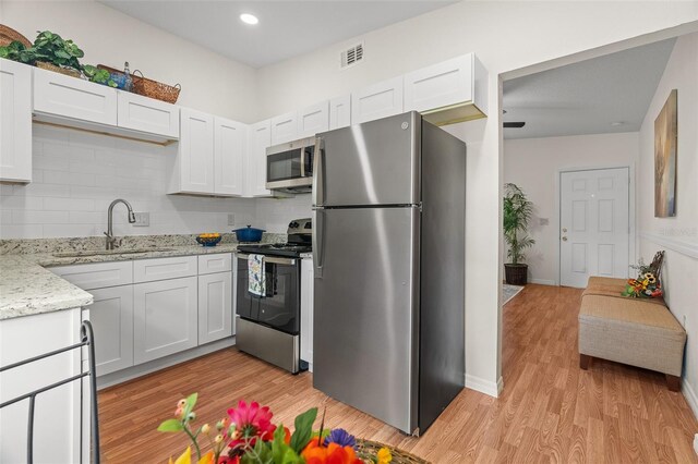 kitchen featuring stainless steel appliances, white cabinetry, a sink, and visible vents