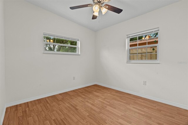 unfurnished room with lofted ceiling, light wood-style floors, ceiling fan, and baseboards