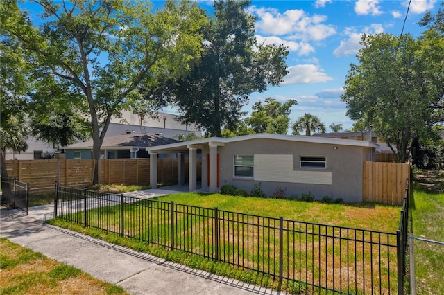 view of front facade featuring a carport, a front yard, a fenced backyard, and stucco siding