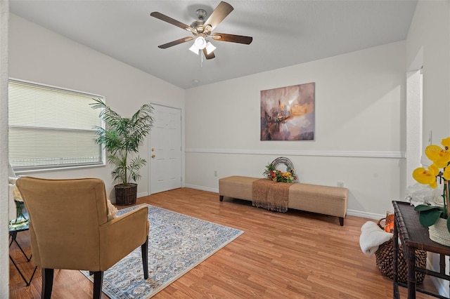 living area featuring baseboards, a ceiling fan, and light wood-style floors