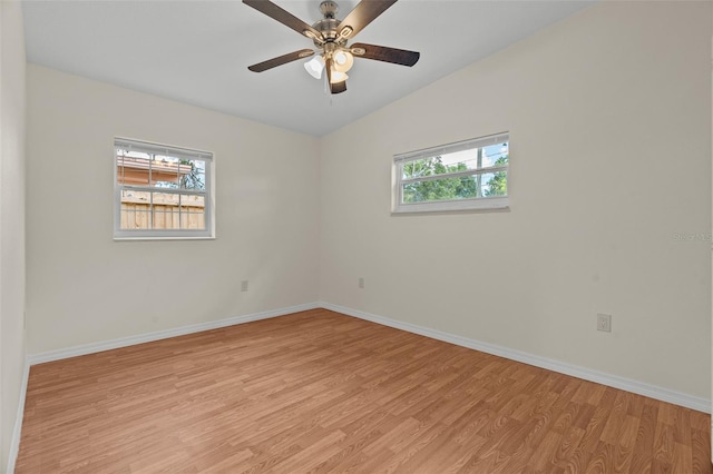 unfurnished room featuring light wood-style floors, a wealth of natural light, vaulted ceiling, and baseboards