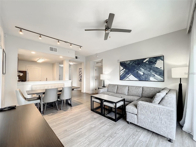 living room featuring ceiling fan, light wood-type flooring, and rail lighting