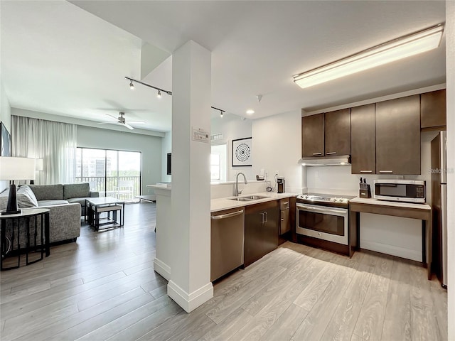 kitchen with stainless steel appliances, track lighting, sink, and light hardwood / wood-style flooring