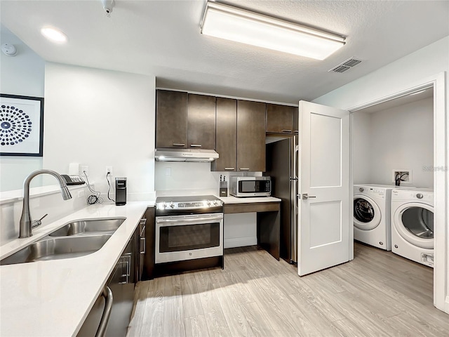 kitchen featuring light hardwood / wood-style floors, appliances with stainless steel finishes, dark brown cabinetry, sink, and washing machine and dryer